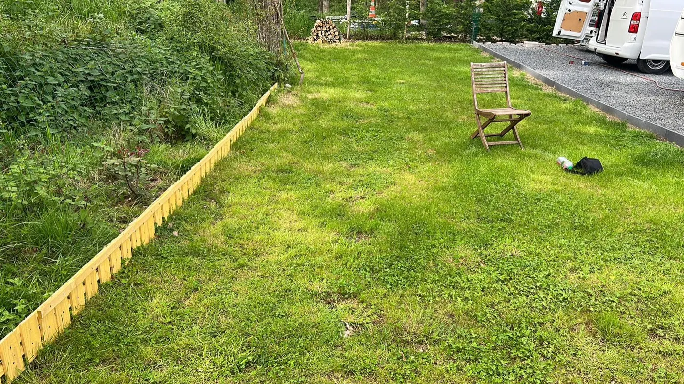 Terrain remis en état après chantier : pelouse dégagée et bordure bois posée