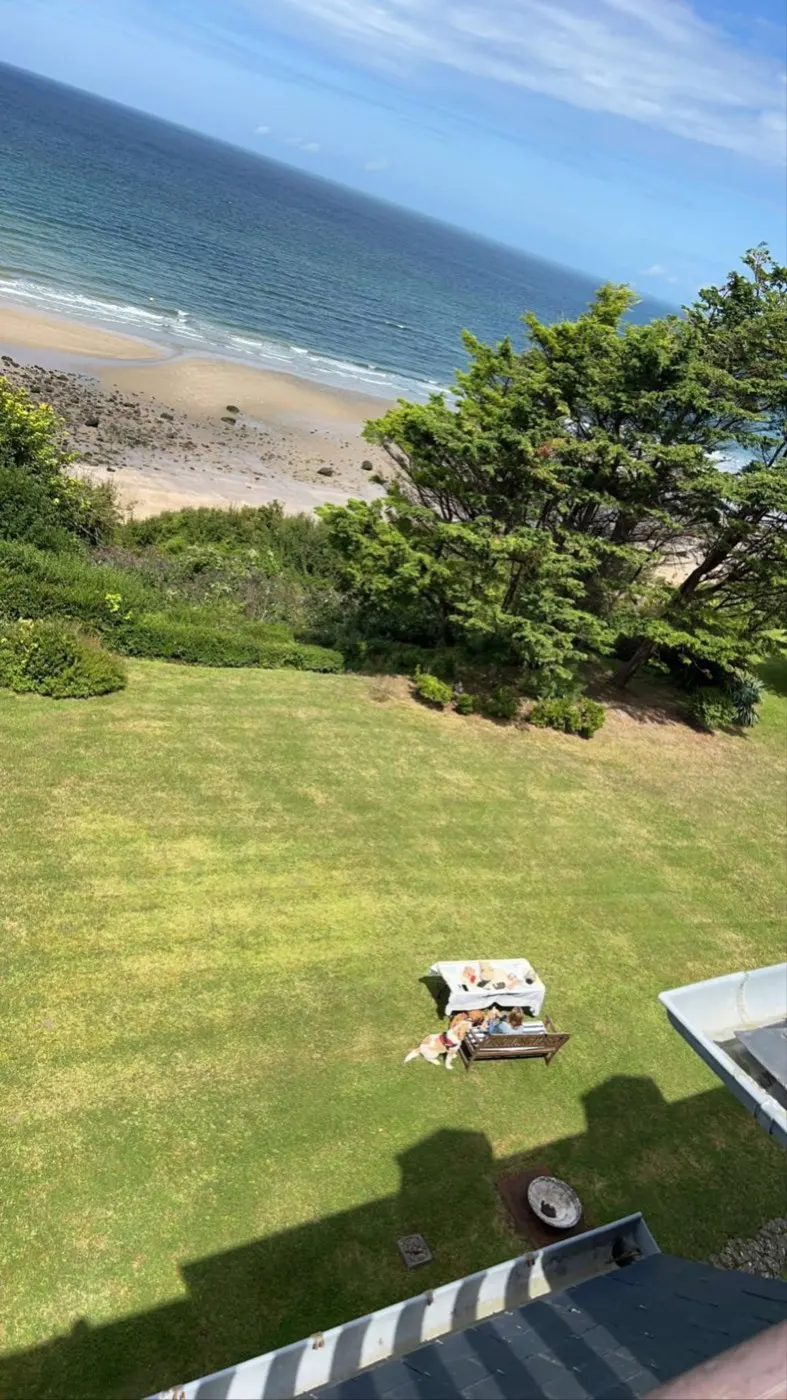 Grand jardin de bord de mer entretenu, arbres taillés en limite de falaise